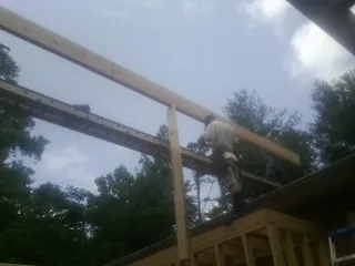 Carpenter setting a ridge beam over a new addition frame — Ice Dam Removal by Roofing Brothers in Spring
